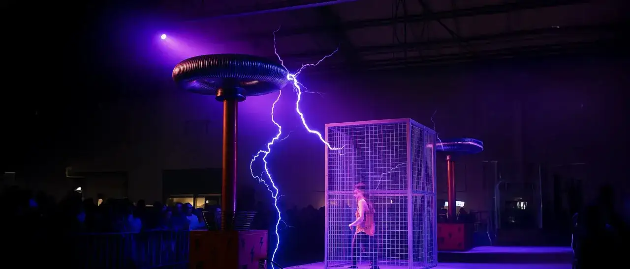 Pokaz z Tesla coil, gdzie błyskawice otaczają klatkę z człowiekiem. To fascynujący odpromiennik energii.